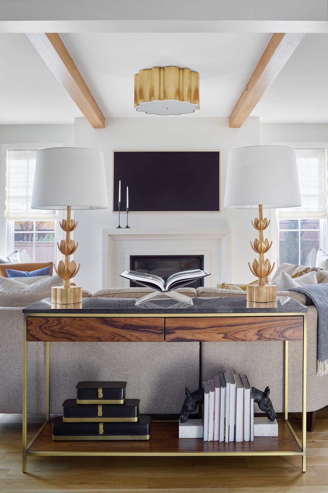 Styled wood console with twin lamps and stacked books behind the sofa in the Bonnie Brae living room, Denver.