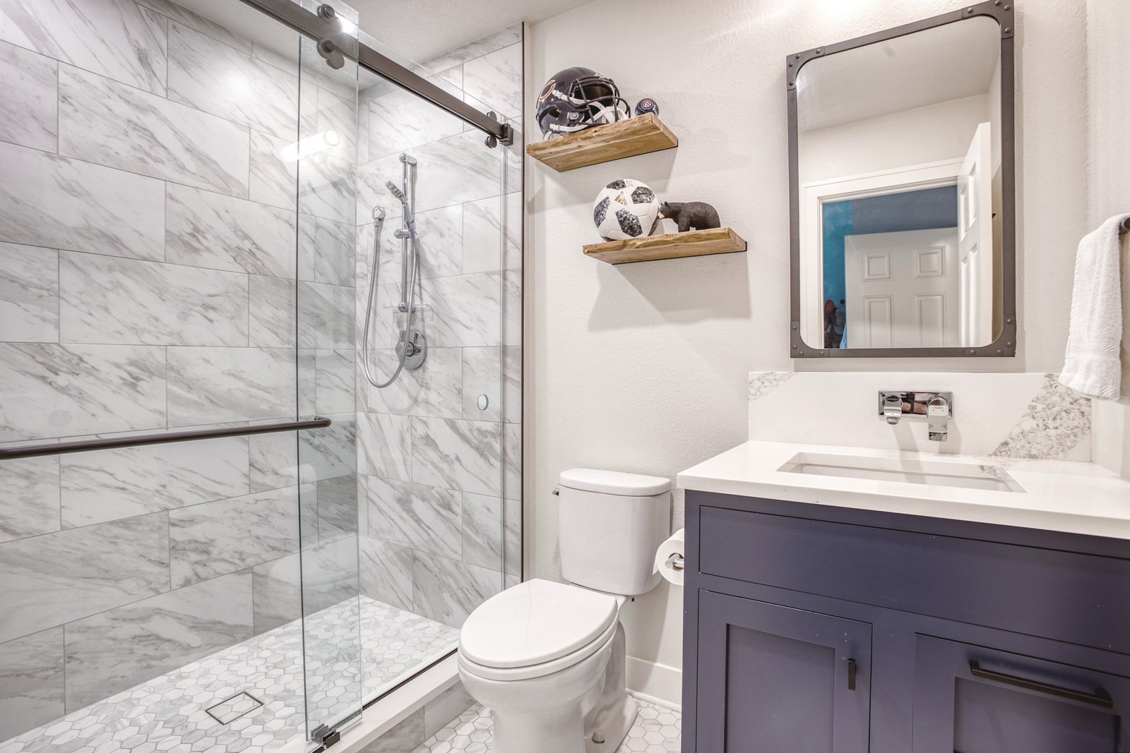 Guest bath with sliding glass shower and navy vanity, Fulton Street whole house renovation in Greenwood Village