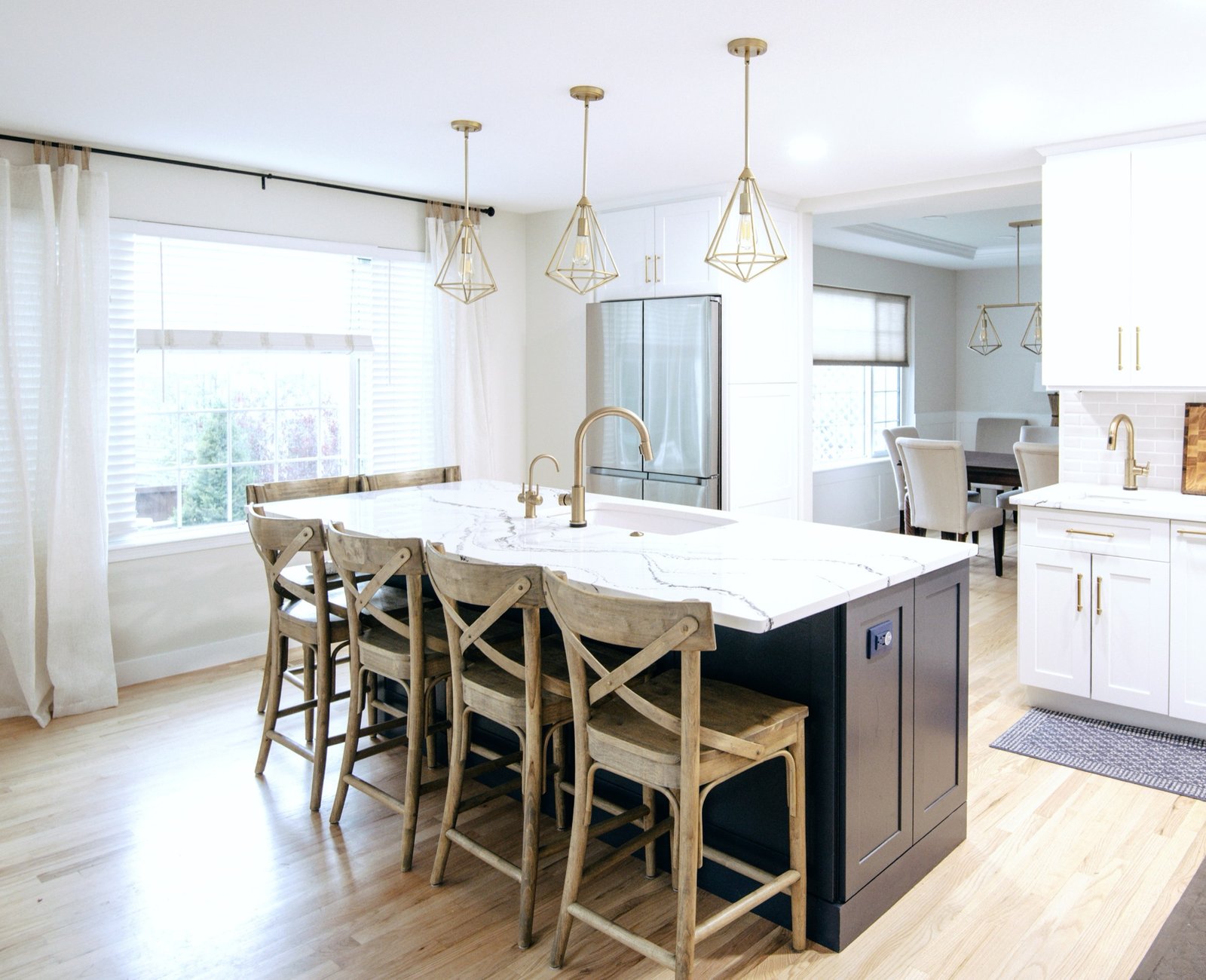 White kitchen with navy island, marble-look quartz, and woven counter stools, Stonegate main floor renovation in Parker, Colorado