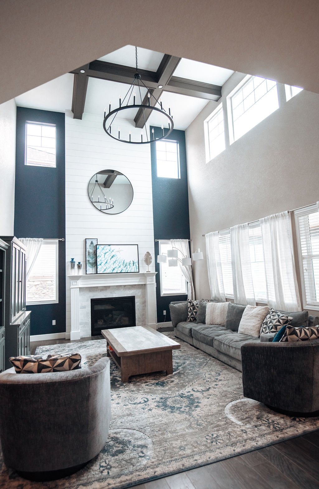 Two-story shiplap fireplace with cast mantle and iron chandelier, Blackstone family room renovation in Aurora, Colorado