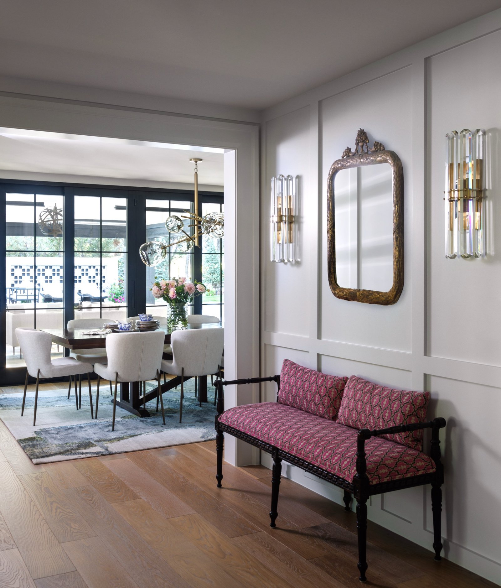 White paneled hallway with antique bench, crystal sconces, and a view to the dining room and pool beyond, Greenwood Village renovation