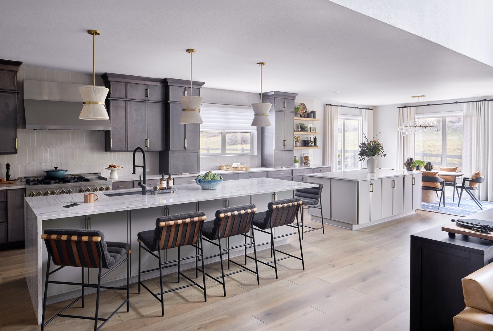 Castle Pines kitchen with double islands, dark cabinetry, marble-look countertops, and breakfast nook in The Canyons new build
