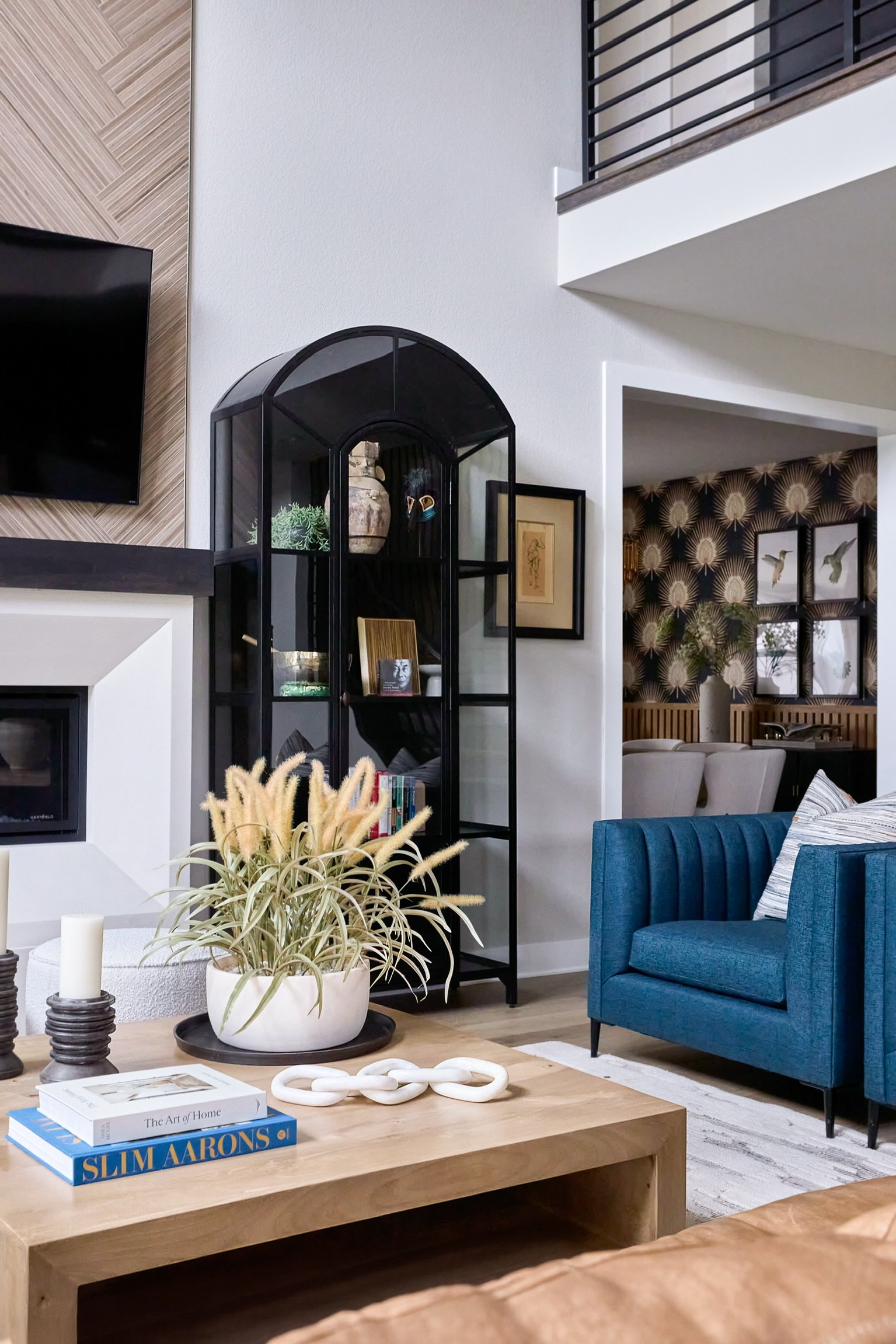 Dining room with black and cream wallpaper, wood slat paneling, black dining table, and chandelier in The Canyons at Castle Pines