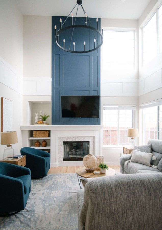 Two-story family room with navy shiplap fireplace, round chandelier, and teal swivel chairs, Stonegate main floor renovation in Parker, Colorado