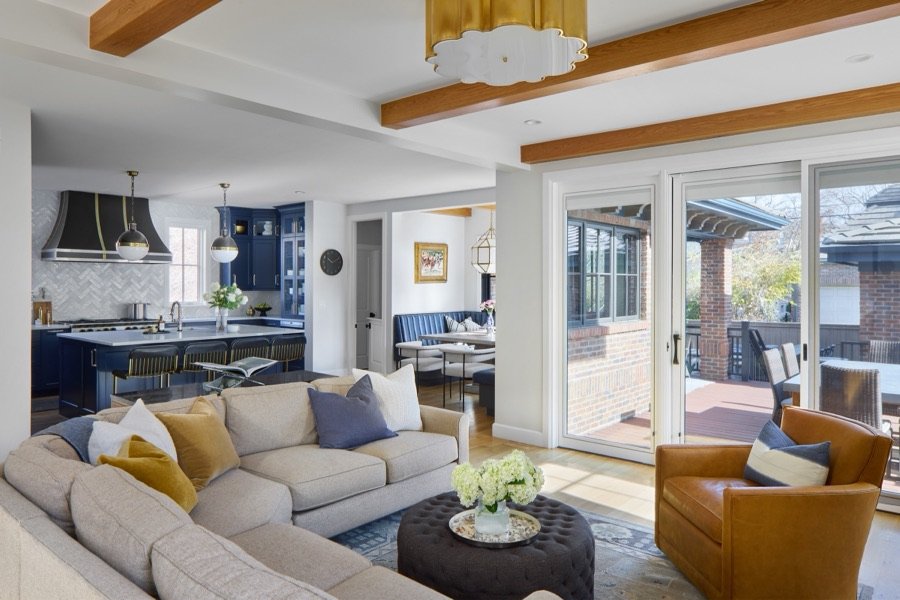 Open family room with cream sectional, camel leather chairs, and a view into the navy kitchen, Bonnie Brae whole home renovation