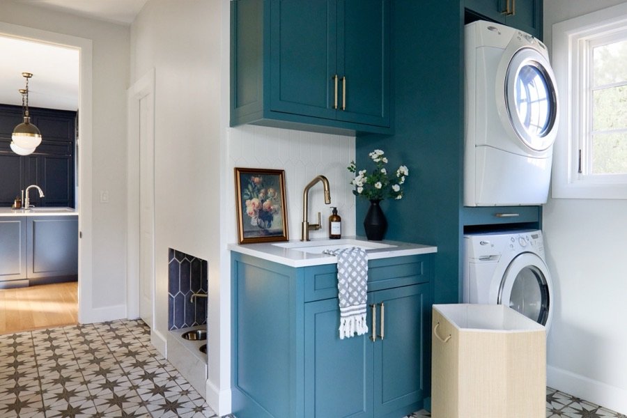 Teal laundry room with patterned cement tile floor and stacked washer and dryer designed by E+E Design Consulting